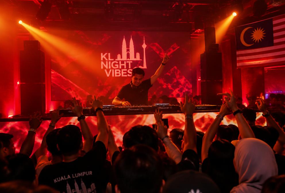 DJ performing at a night event with crowd and orange lighting